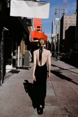 Vestido midi de satén color negro, con cuello halter y cierre de lazada en la nuca. Presenta un diseño fluido con frunces en el escote y corte a la cintura.