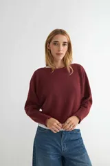 Sweater de punto color bordó, con cuello redondo y mangas largas de corte holgado.