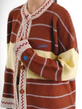 Cardigan tejido de punto jacquard en tonos bordó y rojo con rayas, de corte oversize, cuello redondo y cierre frontal con botones carey. Presenta detalles bordados en contraste y monograma en la espalda.