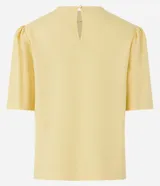 Blusa de viscolino color amarillo pálido, con cuello redondo y mangas cortas abullonadas.