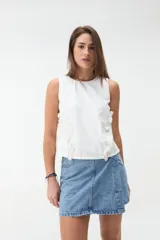 Blusa de denim blanco sin mangas, con cuello redondo y volados a lo largo de las costuras laterales.