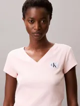 Remera de Calvin Klein confeccionada en algodón elástico con textura de canalé fino. Presenta un diseño de corte slim, cuello en V, manga corta y una insignia con el logo de la marca en el pecho.