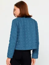 Chaqueta de algodón en color beige con diseño acolchado de costuras decorativas. Presenta cuello clásico, cierre frontal con botones metálicos y bolsillos frontales aplicados.