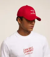 Gorra roja de sarga con visera curva, hebilla ajustable en la parte trasera y bordado frontal con la frase "Nosotros Dos y Un Boteco".