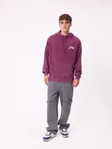 Canguro con capucha de color bordó, con diseño estampado en la espalda en tonos amarillos y blancos, y detalle de parche en la manga. Posee corte holgado y puños elásticos.