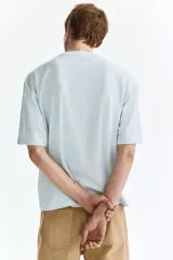 Remera de algodón en punto pesado, color celeste, de corte boxy, cuello redondo ribeteado, hombros caídos y mangas cortas.
