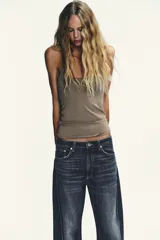 Jeans de tiro medio con diseño baggy barrel, cinco bolsillos y costuras laterales torcidas. Presenta cierre frontal con cremallera y botón metálico.