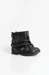 Botas de cuero negro con caña media y diseño holgado con efecto fruncido en la parte superior. Presentan una suela plana con taco bajo y puntera redondeada.