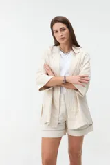Blazer negro de corte recto y holgado, con doble botonadura frontal, solapas clásicas y mangas tres cuartos con costuras pespunteadas en contraste.