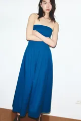 Vestido midi de popelín en color azul, con escote palabra de honor y falda con pliegues que aportan volumen. Cuenta con cierre lateral mediante cremallera oculta.