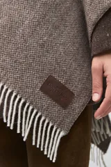 Ruana de lana sin teñir en tono marrón jaspeado, con diseño envolvente y terminaciones de flecos en color crudo.
