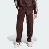 Pantalón deportivo Adidas color marrón, con diseño de monograma grabado en relieve en todo el tejido, franjas laterales blancas y el logo de la marca bordado en la cadera.