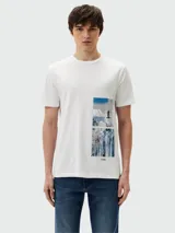 Camiseta blanca de manga corta marca BOSS, con estampado rectangular vertical en el lateral izquierdo que incluye una fotografía de paisaje urbano en tonos azules y grises.