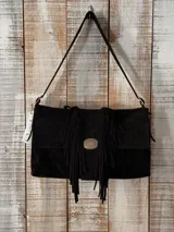 Cartera de cuero negro con flecos frontales, solapa con hebilla metálica decorativa y correa de hombro ajustable.