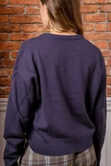 Sweater de punto color gris oscuro con diseño de rombos formados por lentejuelas brillantes, cuello redondo y mangas largas con puños acanalados.