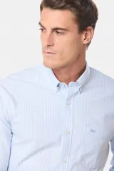 Camisa de vestir celeste con rayas verticales blancas, de corte clásico, con cuello abotonado y bolsillo en el pecho.