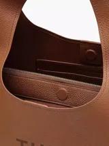 Bolso tipo saco de cuero color camel, con correa ancha para llevar al hombro. Presenta el logo de la marca grabado en relieve en el frente.