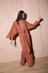 Vestido largo marrón tipo kimono en crepé texturado, con mangas amplias abiertas y tiras ajustables para atar en la cintura.