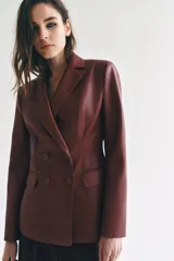 Blazer de cuero sintético en color beige, con cuello solapa, manga larga y bolsillos con solapa en el frente. Cierre frontal cruzado con botones a tono.