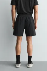 Pantalones deportivos cortos de tejido técnico ligero y elástico, con cintura elástica ajustable, bolsillos frontales y aberturas laterales en el bajo.