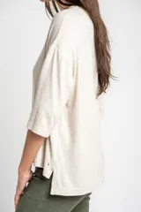 Remera color arena con efecto melange, de corte oversize, cuello redondo y mangas 3/4.