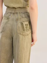 Enterito largo de denim color verde militar, sin mangas, con cuello camisero, cierre frontal completo y bolsillos laterales. Incluye cinturón ajustable del mismo material con hebilla metálica.