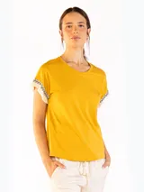 Remera color naranja de manga corta, confeccionada en algodón, con detalles de flecos y bordado en las mangas.