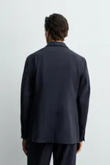Blazer de corte regular confeccionado en lana de origen italiano. Presenta cuello con solapas de muesca, cierre frontal de un botón, bolsillos laterales con solapa y bolsillo de vivo en el pecho. Incluye abertura central en la espalda y forro interior.