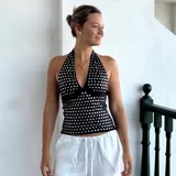 Top negro sin mangas con cuello halter y escote en V, adornado con tachas metálicas plateadas en toda la prenda.
