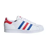Championes Adidas Superstar blancos con detalles en azul y rojo. Presentan las tres tiras características de Adidas en los laterales en azul y rojo, y refuerzo de talón en rojo con la palabra "STAR" en blanco. La puntera es de goma con textura.