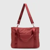 Bolso tipo tote de la marca Bubba, color rojo, con diseño funcional y espacioso. Cuenta con asas cortas fijas y una correa larga ajustable y extraíble, ambas con el logo de la marca estampado. Presenta un bolsillo frontal pequeño y cierre superior.
