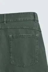 Bermuda tipo jorts de algodón color verde oscuro, con corte relajado y tiro medio. Presenta bolsillos frontales y bolsillos traseros de plastrón.