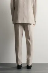 Pantalón de traje regular fit de lino color verde militar, con bolsillos laterales y bolsillos traseros de doble vivo con botón. Cierre frontal con cremallera y botón.