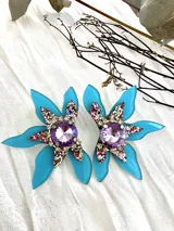 Par de aros con forma de flor celeste, centro con strass y cristal amatista.