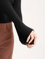Polera negra de tejido de punto acanalado, con cuello alto y mangas largas.