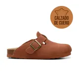 Zueco casual de cuero gamuzado color marrón, con diseño destalonado y punta redonda. Cuenta con una tira con hebilla metálica ajustable en el lateral exterior y suela de corcho y goma.
