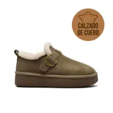 Zapato tipo zueco de cuero gamuzado color tostado, con interior forrado en piel sintética blanca. Presenta una tira ajustable con hebilla metálica dorada sobre el empeine y una suela de plataforma de goma color marrón.
