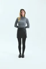 Minifalda negra de ecocuero con textura croco, cierre metálico lateral y tajo en la pierna derecha.