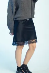 Minifalda de satén negro con detalle de encaje en el borde inferior.