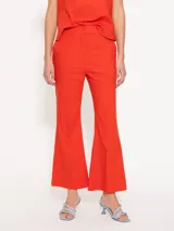 Pantalon de corte flare en color rojo, con tiro medio, cierre frontal con gancho y boton interno, y costuras verticales decorativas en el frente.