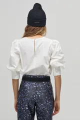 Blusa blanca de algodón con mangas abullonadas tres cuartos y detalle de pinzas en los hombros.