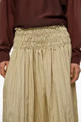 Falda midi de corte en A y silueta fluida, color beige, con diseño de frunces hasta la cadera que aporta movimiento.