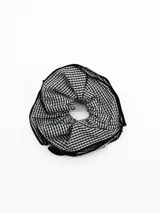 Colita para el pelo tipo scrunchie con diseño de cuadros vichy en blanco y negro, con borde decorativo en color negro.