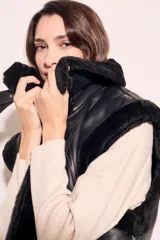 Chaleco negro de cuero sintético con cuello de piel sintética y cierre frontal con cremallera.