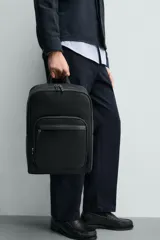 Mochila de diseño minimalista en color negro con acabado grabado. Cuenta con compartimento principal con cierre, bolsillo frontal con cierre, asa de mano superior y correas de hombro ajustables y acolchadas. Incluye espacio interior para dispositivos electrónicos y bolsillo de seguridad trasero.