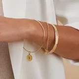 Esclava de alambre redondo en oro 9k con medalla colgante circular que presenta un diseño de estrella grabada con una circonia central.