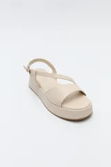 Sandalia negra con plataforma, tiras cruzadas sobre el empeine y pulsera ajustable al tobillo.