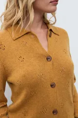 Cardigan de punto color ocre, con diseño calado de pequeños motivos florales, cuello polo y cierre frontal con botones.