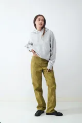 Pantalón de tiro medio color verde oliva, confeccionado en tejido con efecto gamuza. Presenta cierre frontal con cremallera, presillas para cinturón y corte recto.