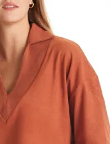 Buzo de punto suave marca Cyrus, color blanco, con cuello solapa y escote en V. Presenta diseño de hombros caídos, mangas 3/4 con puños largos de tejido rib al tono y corte holgado con tajos laterales en el ruedo.